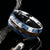 9mm wide ring for men with blue and black cobaltium mokume edges and a dinosaur bone inlay
