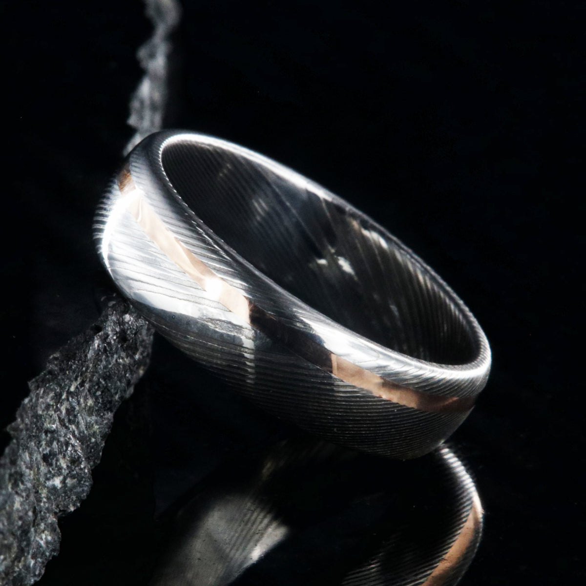 6mm wide white Damascus steel wedding band with rounded profile and off-centered rose gold inlay