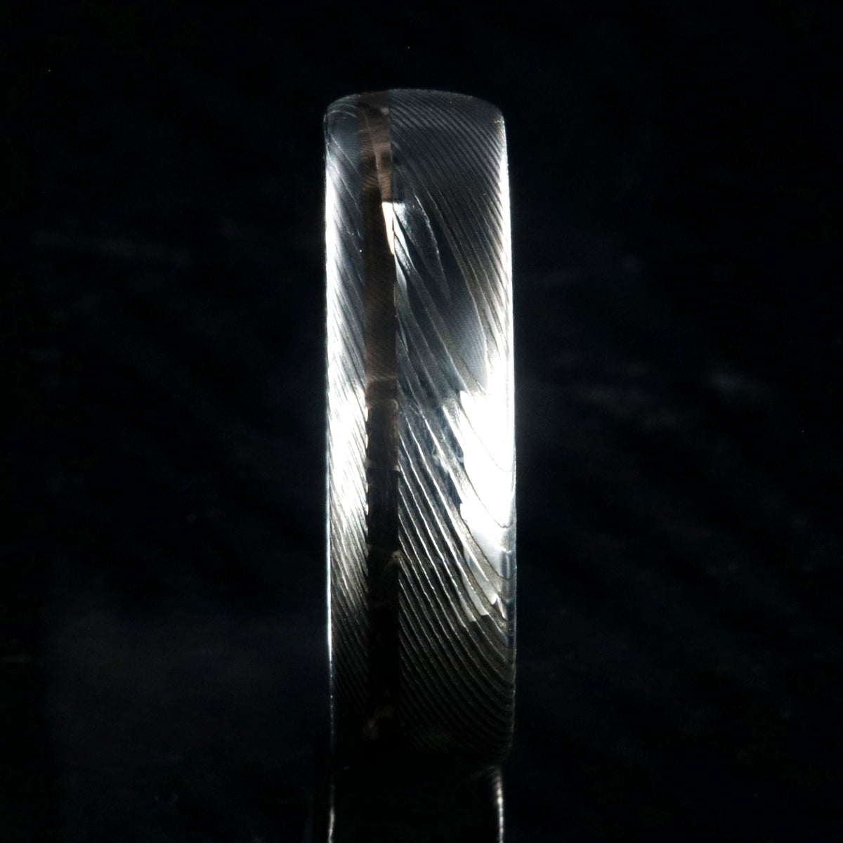 6mm wide white Damascus steel wedding band with rounded profile and off-centered rose gold inlay