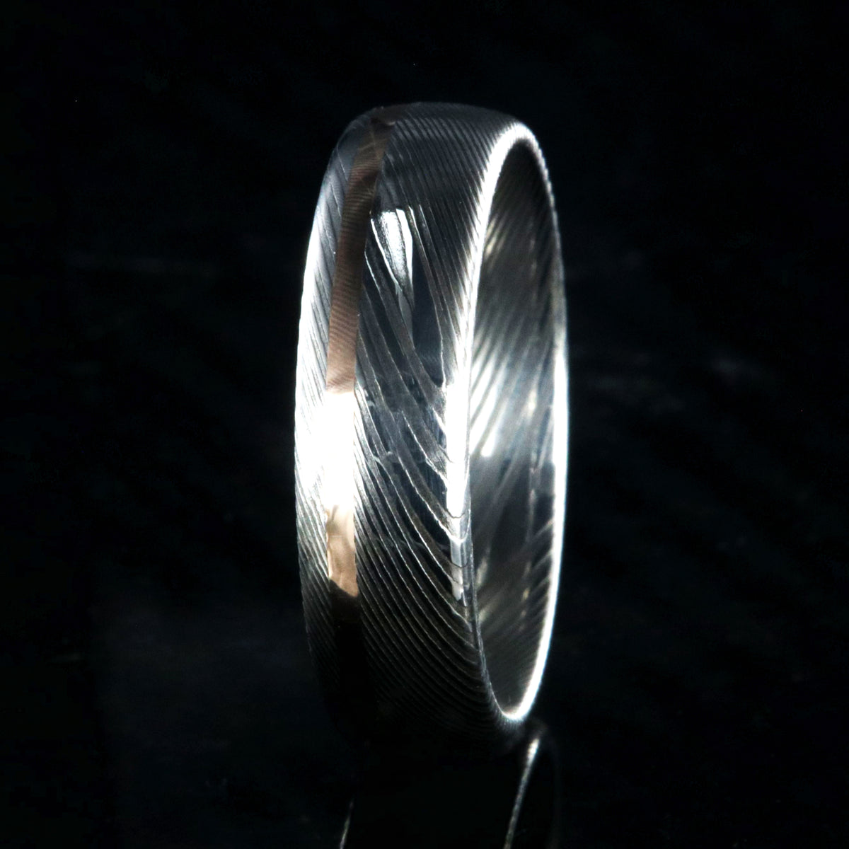 6mm wide white Damascus steel wedding band with rounded profile and off-centered rose gold inlay