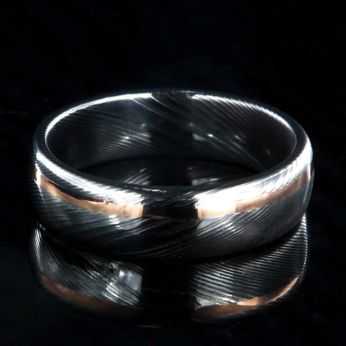 6mm wide white Damascus steel wedding band with rounded profile and off-centered rose gold inlay