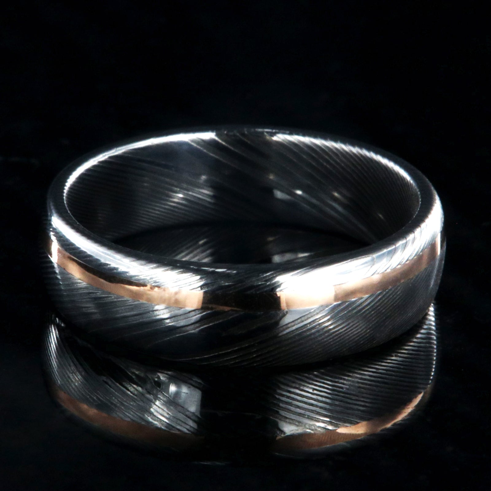 6mm wide white Damascus steel wedding band with rounded profile and off-centered rose gold inlay