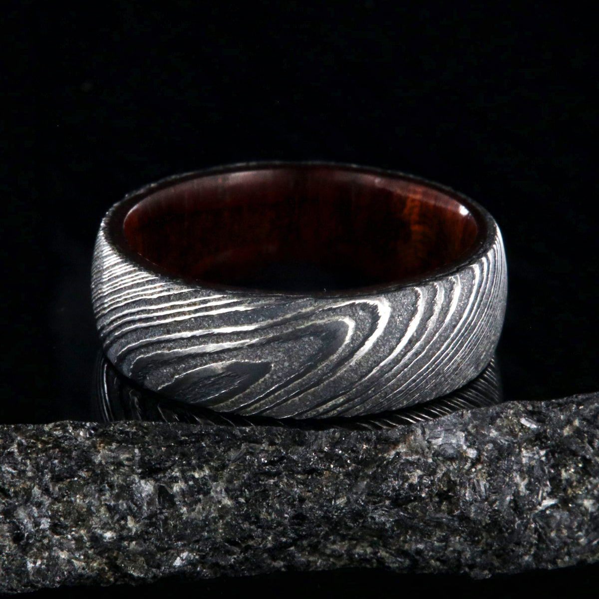 7mm wide black Damascus steel wedding band with a bloodwood sleeve with a rounded profile