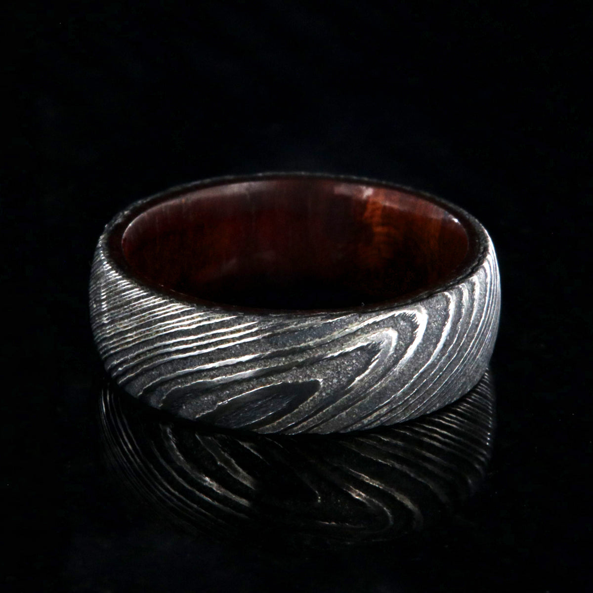 7mm wide black Damascus steel wedding band with a bloodwood sleeve with a rounded profile