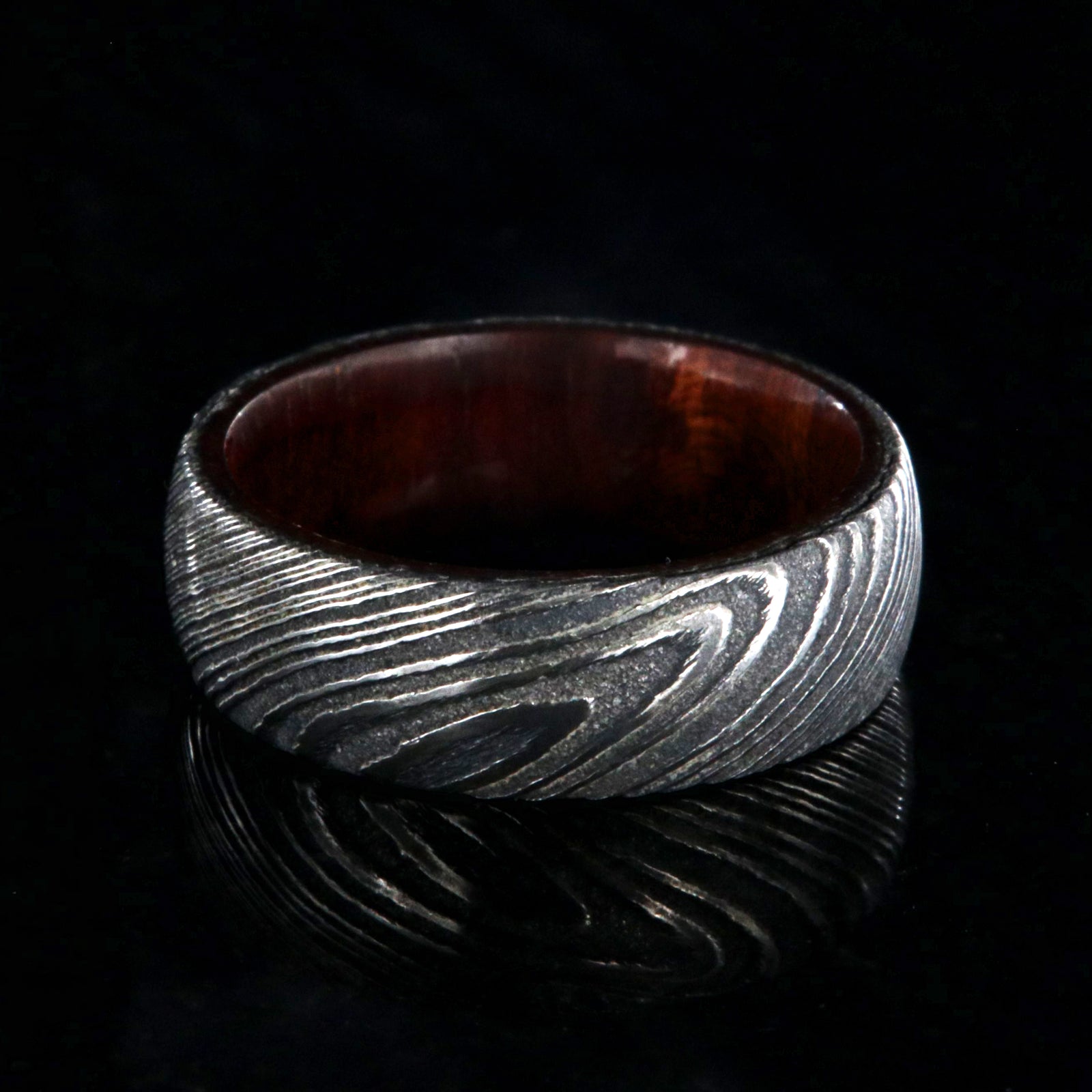 7mm wide black Damascus steel wedding band with a bloodwood sleeve with a rounded profile
