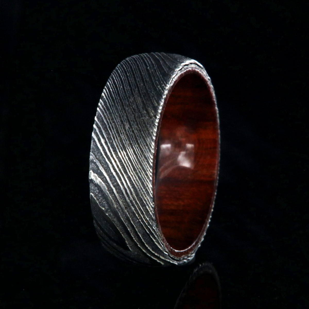 7mm wide black Damascus steel wedding band with a bloodwood sleeve with a rounded profile