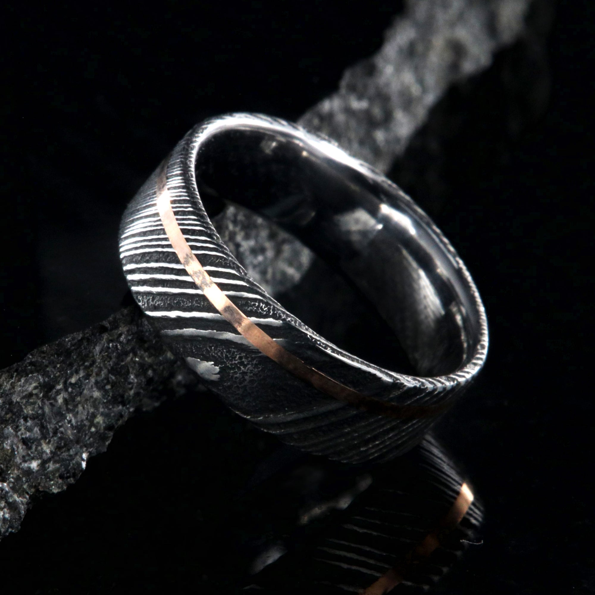 7mm wide black Damascus steel wedding ring with rose gold and flat profile