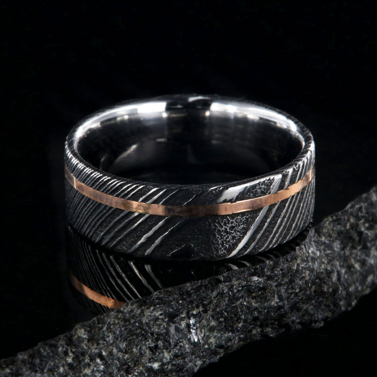 7mm wide black Damascus steel wedding ring with rose gold and flat profile