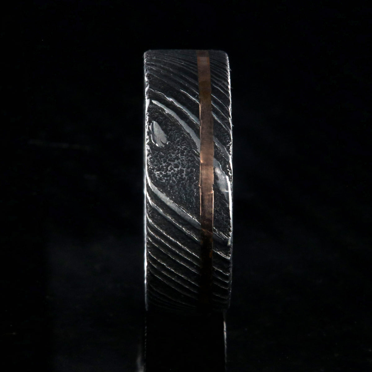 7mm wide black Damascus steel wedding ring with rose gold and flat profile
