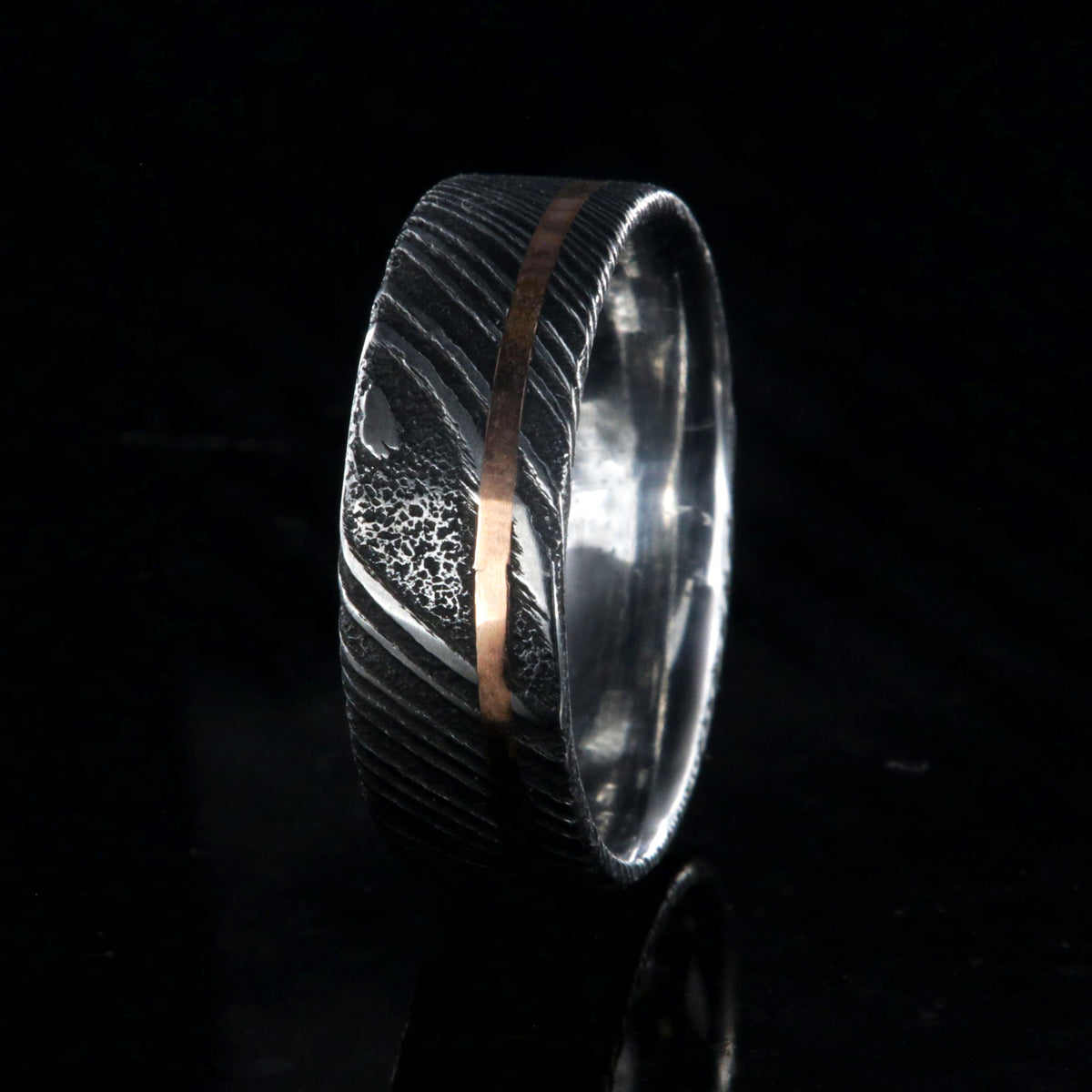 7mm wide black Damascus steel wedding ring with rose gold and flat profile