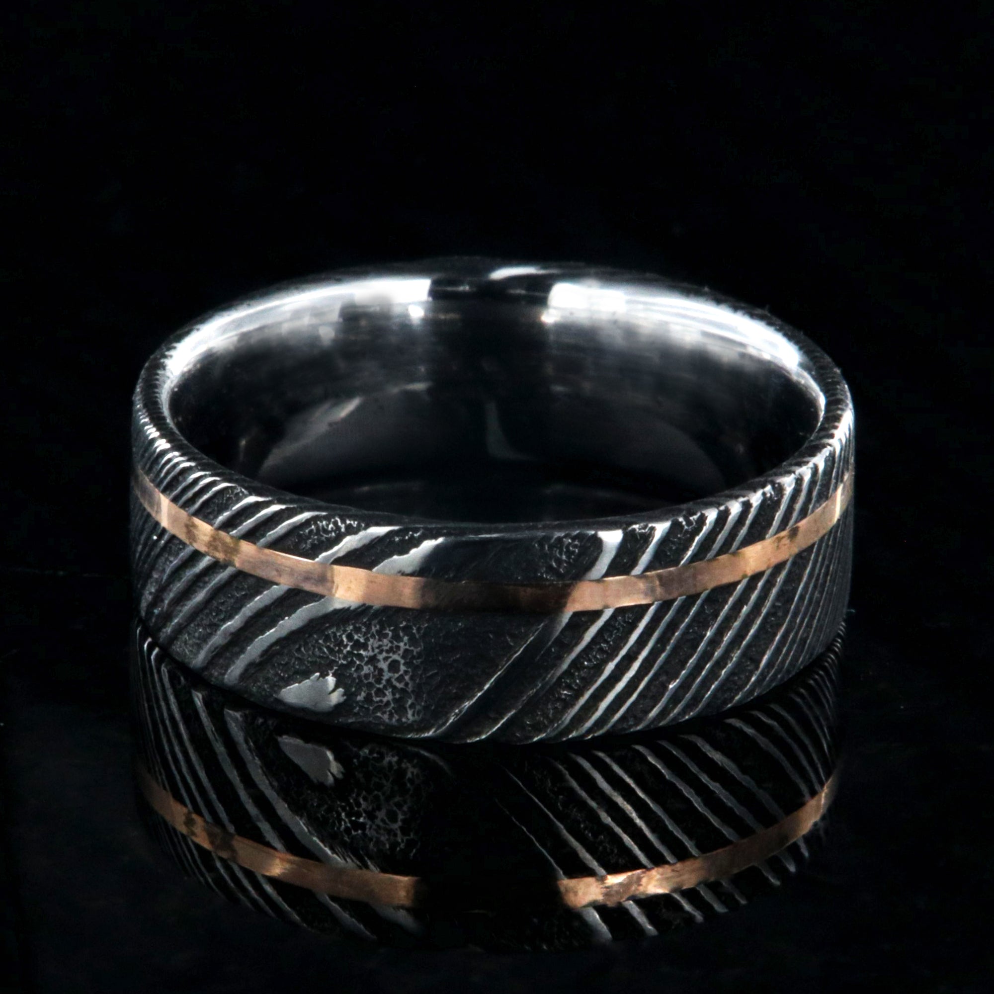 7mm wide black Damascus steel wedding ring with rose gold and flat profile