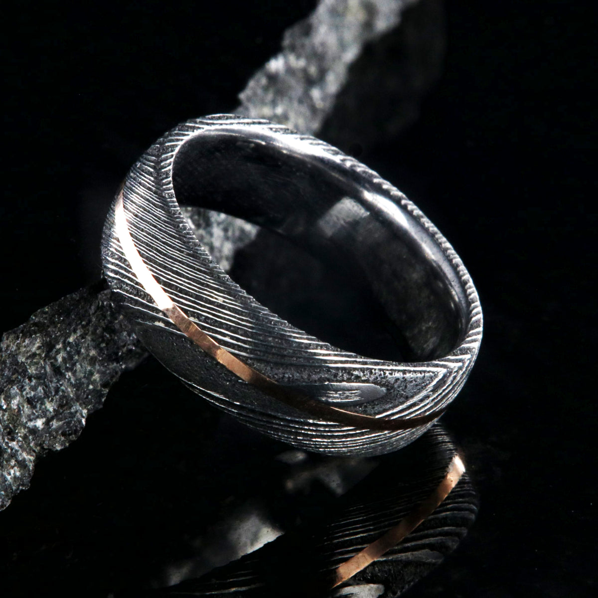 7mm wide black Damascus steel men&#39;s wedding band with centered rose gold inlay and polished inside