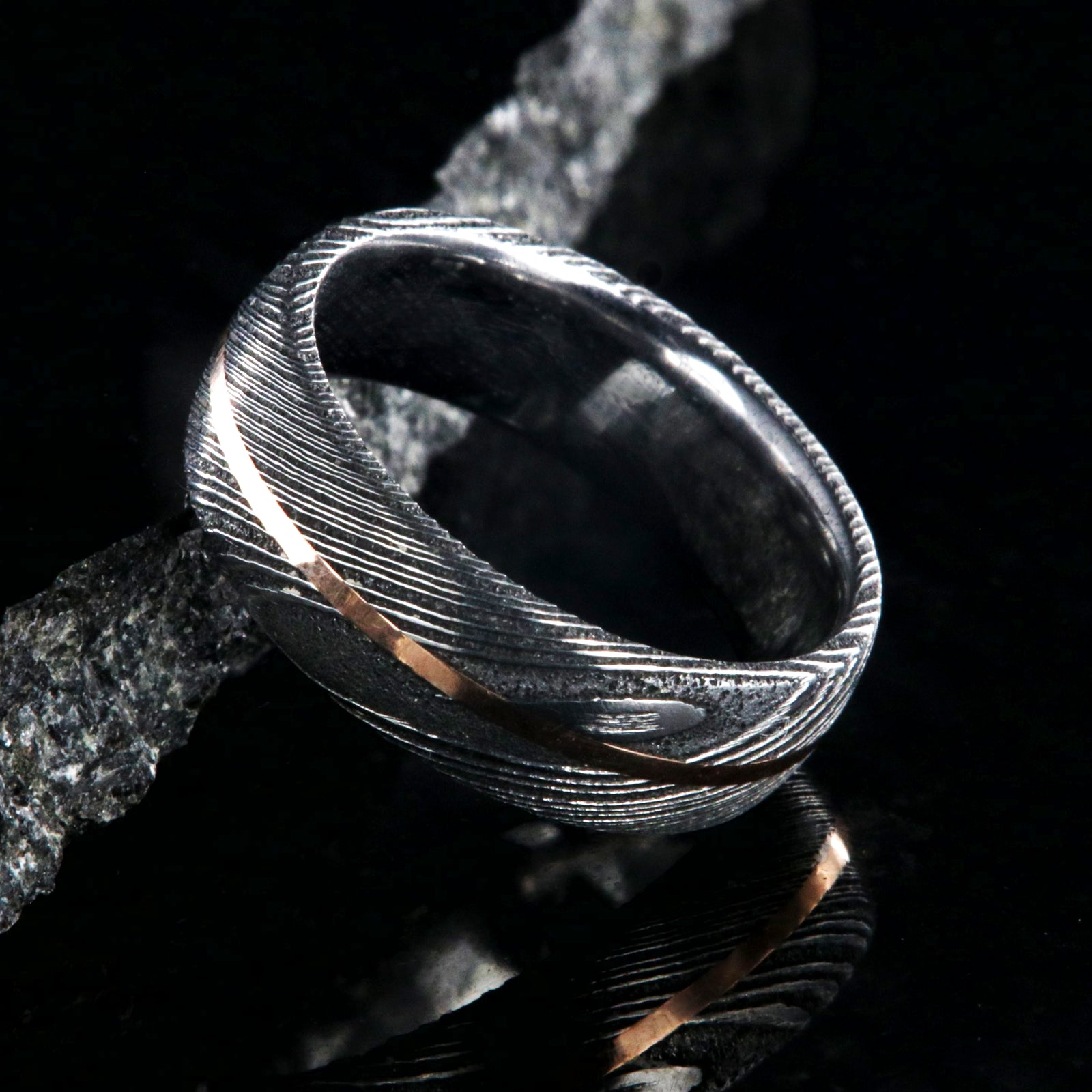 7mm wide black Damascus steel men's wedding band with centered rose gold inlay and polished inside