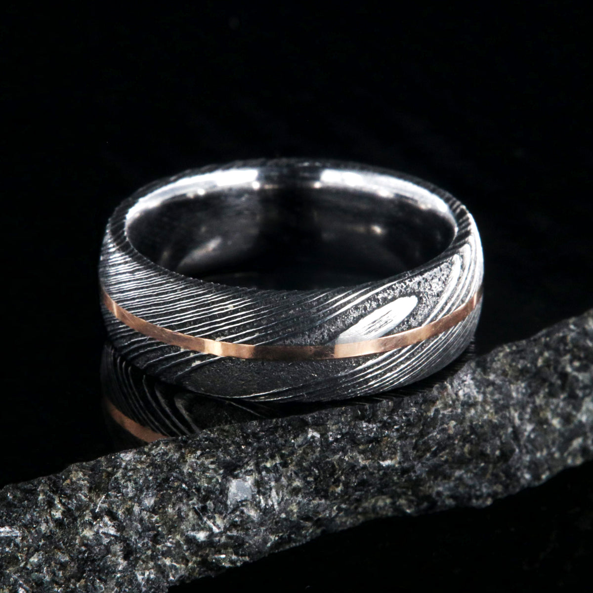 7mm wide black Damascus steel men&#39;s wedding band with centered rose gold inlay and polished inside