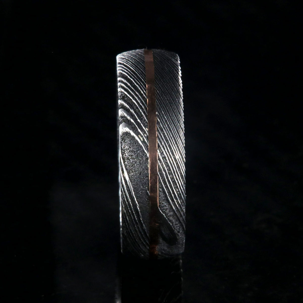 7mm wide black Damascus steel men&#39;s wedding band with centered rose gold inlay and polished inside