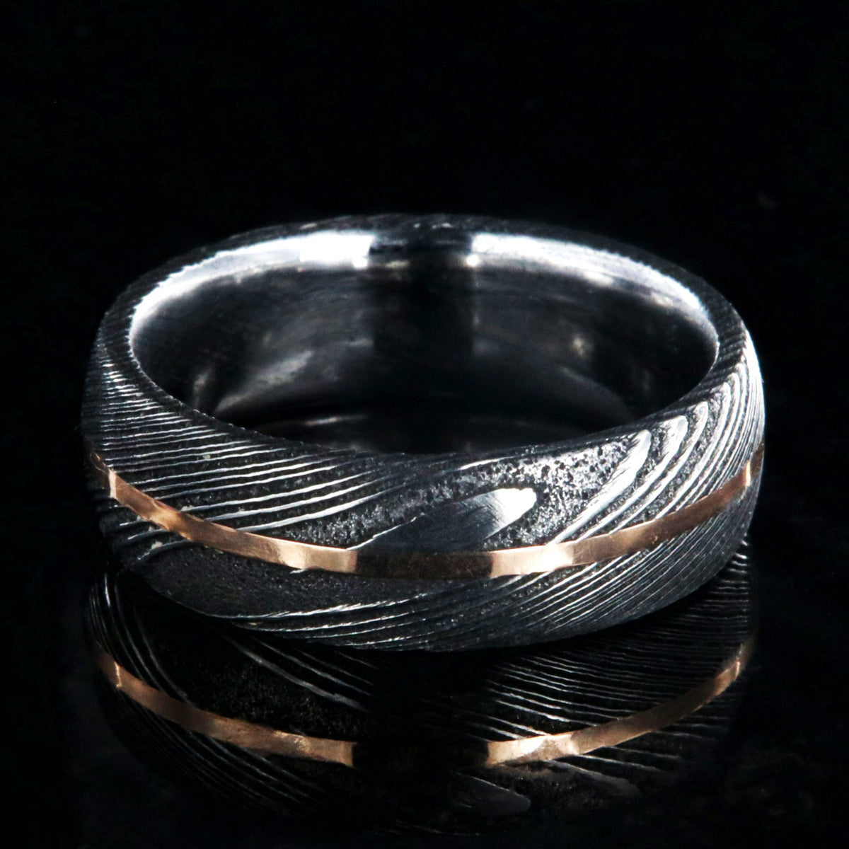 7mm wide black Damascus steel men&#39;s wedding band with centered rose gold inlay and polished inside