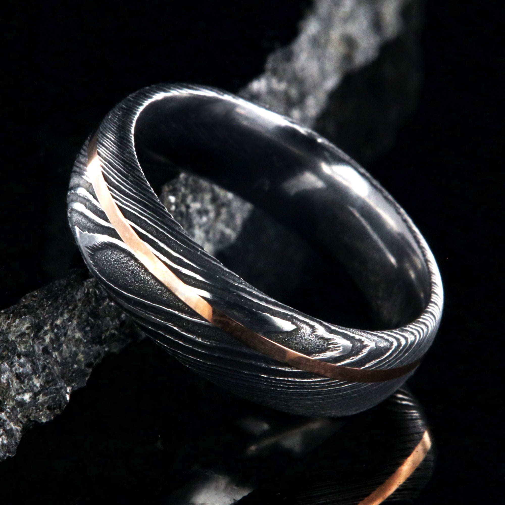 7mm wide black Damascus steel men's wedding ring with thin rose gold inlay