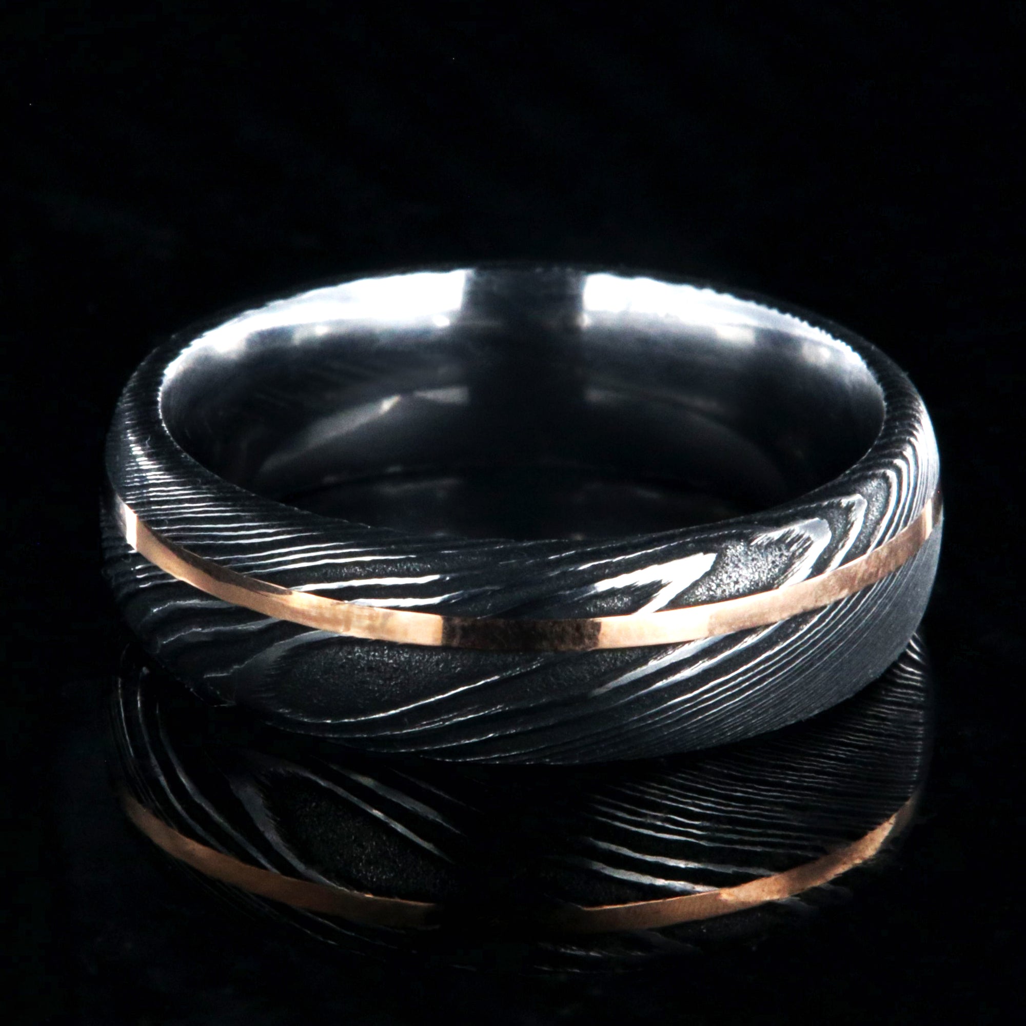 7mm wide black Damascus steel men's wedding ring with thin rose gold inlay