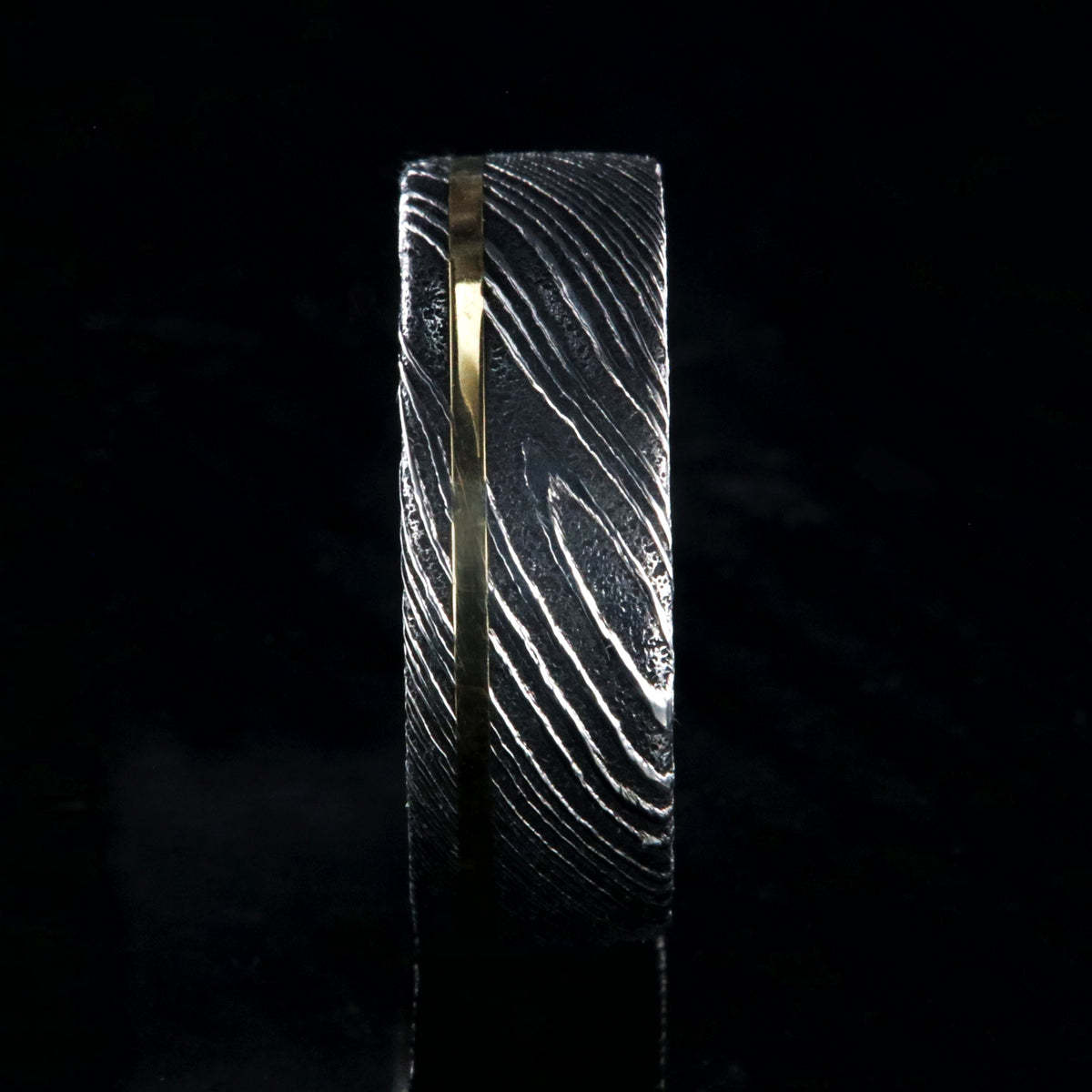 8mm wide black Damascus steel ring with a flat profile, polished inside, and a thin off-centered rose gold inlay