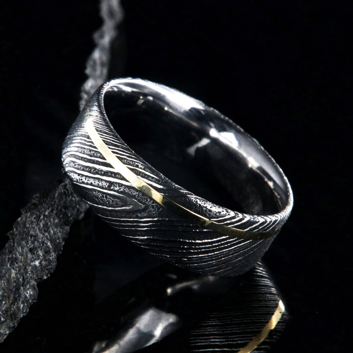 8mm wide black Damascus steel ring with a flat profile, polished inside, and a thin off-centered rose gold inlay