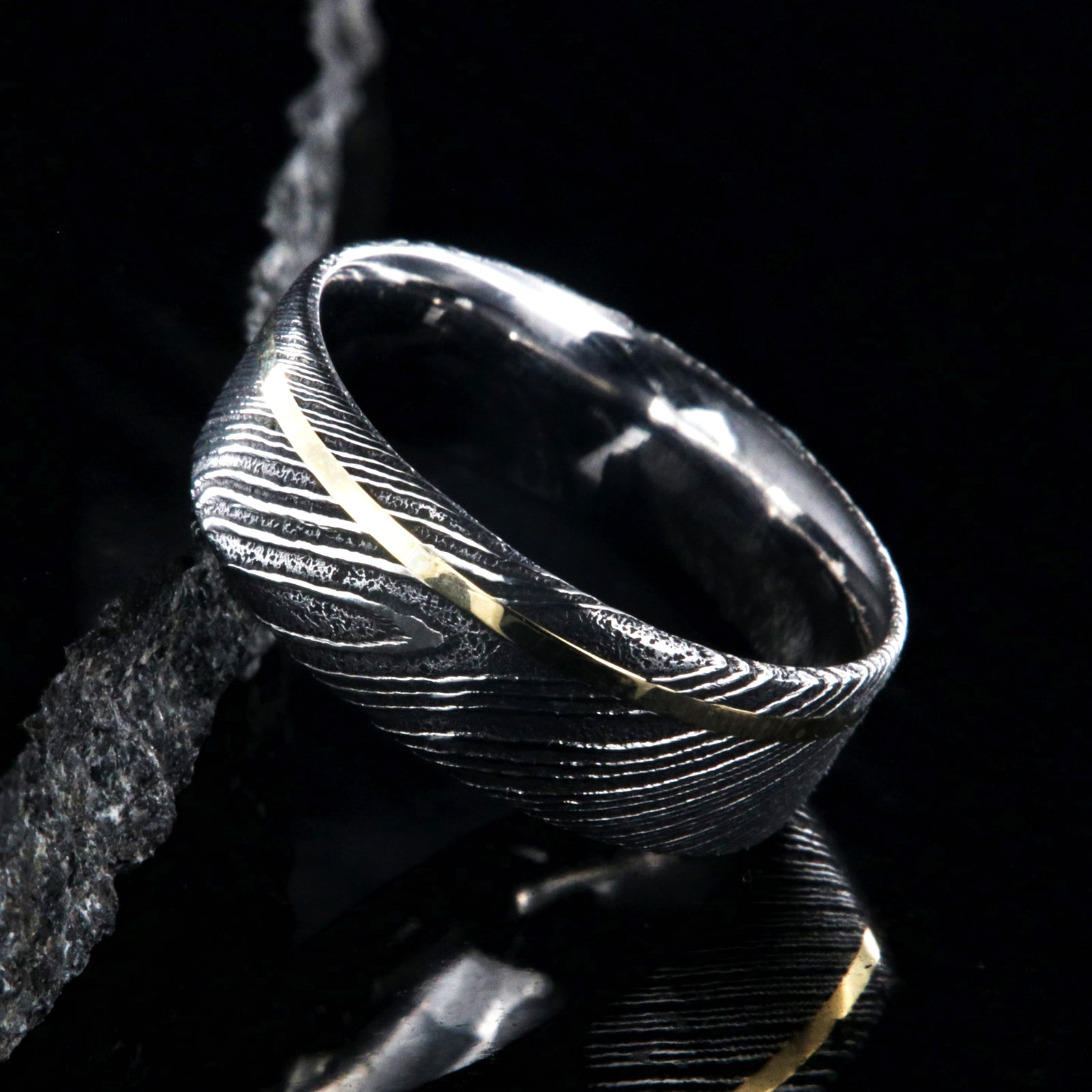 8mm wide black Damascus steel ring with a flat profile, polished inside, and a thin off-centered rose gold inlay
