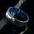 8mm wide black Damascus steel ring with a swirled blue acrylic sleeve and white gold inlay