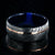 8mm wide black Damascus steel ring with an off-center rose gold inlay and dark blue acrylic sleeve