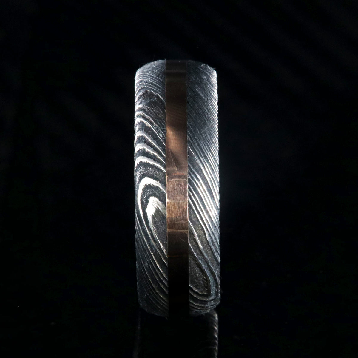 8mm wide black Damascus steel wedding band with a centered rose gold inlay and rounded profile