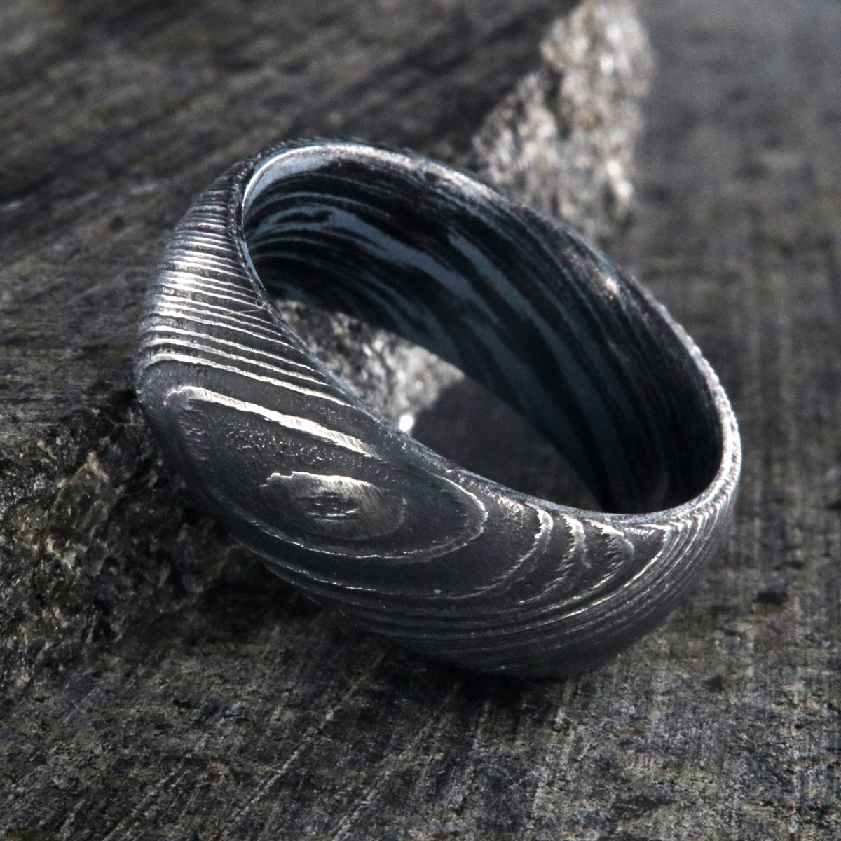 8mm wide Damascus steel wedding ring for men with a blue and black swirled cobaltium mokume sleeve