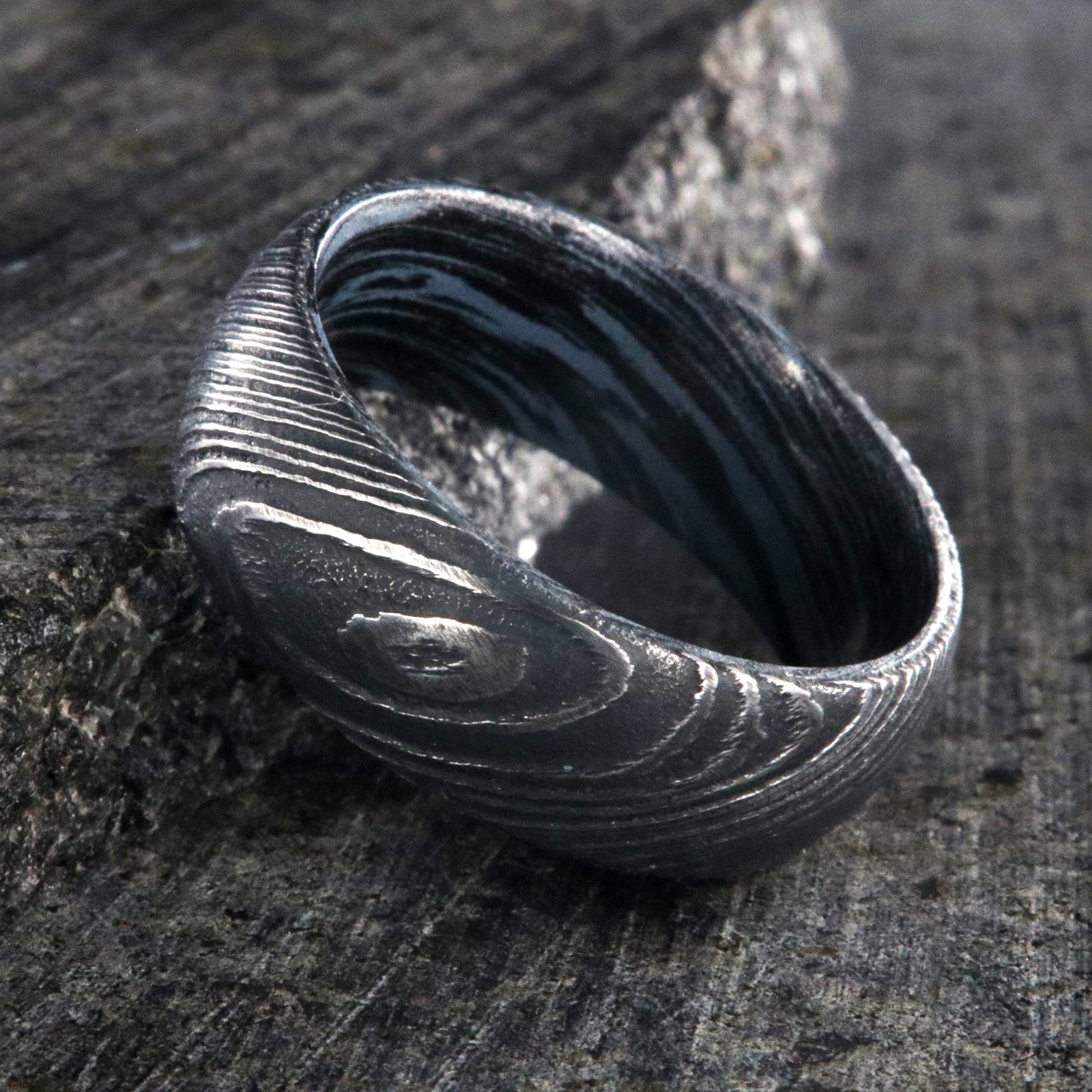 8mm wide Damascus steel wedding ring for men with a blue and black swirled cobaltium mokume sleeve