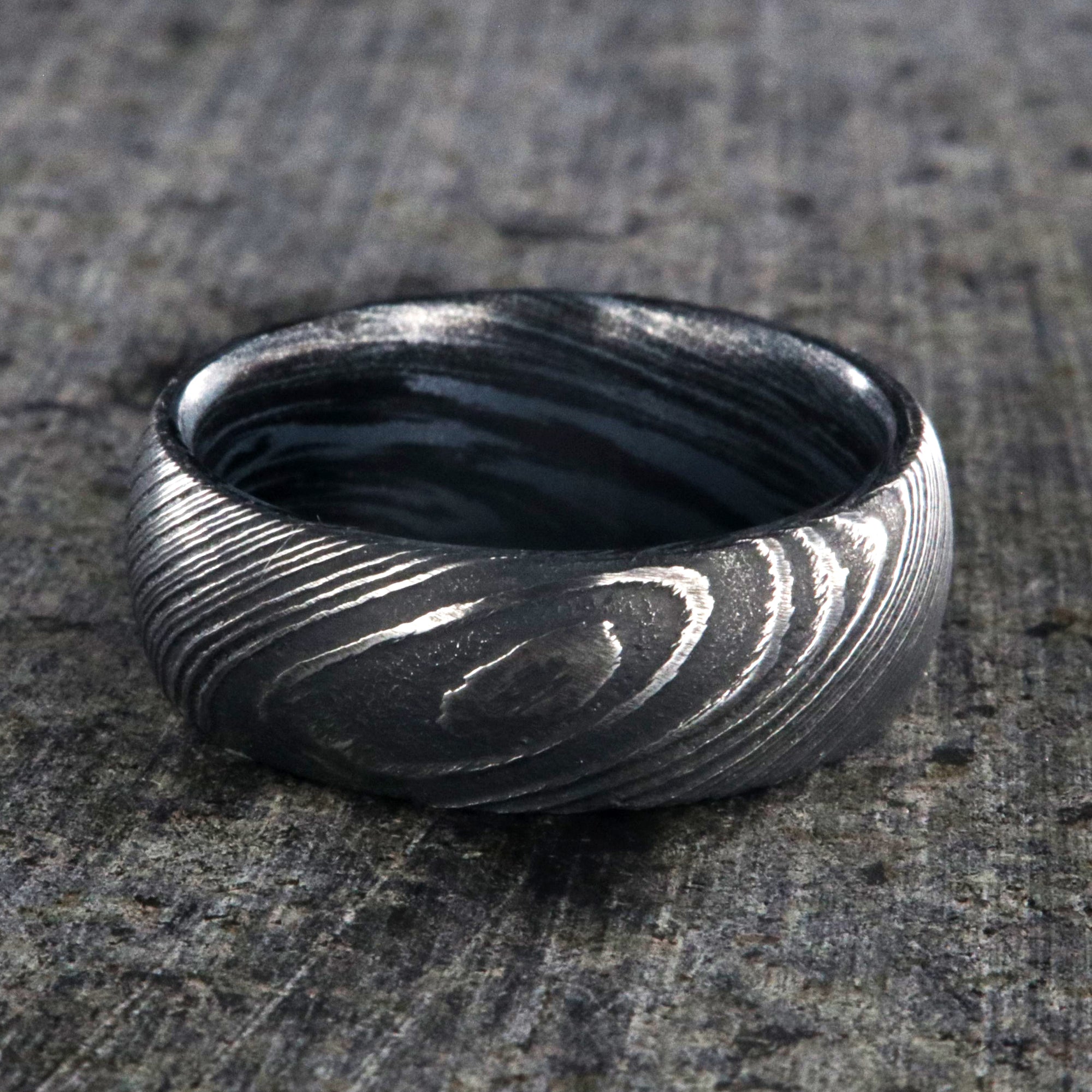 8mm wide Damascus steel wedding ring for men with a blue and black swirled cobaltium mokume sleeve