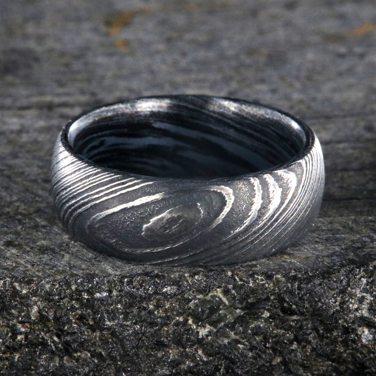 8mm wide Damascus steel wedding ring for men with a blue and black swirled cobaltium mokume sleeve