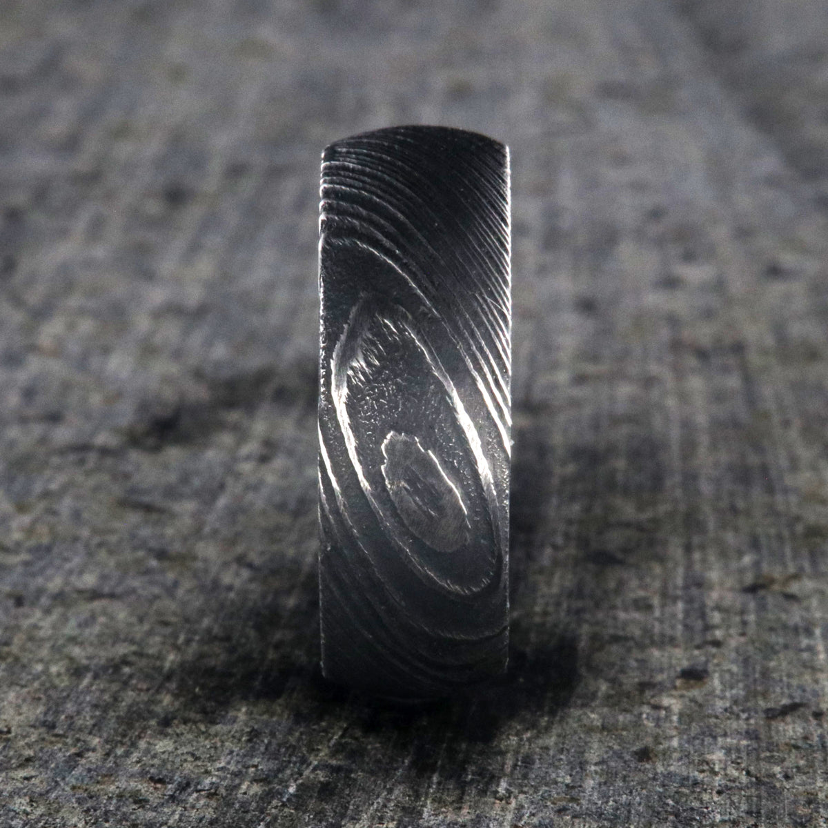 8mm wide Damascus steel wedding ring for men with a blue and black swirled cobaltium mokume sleeve