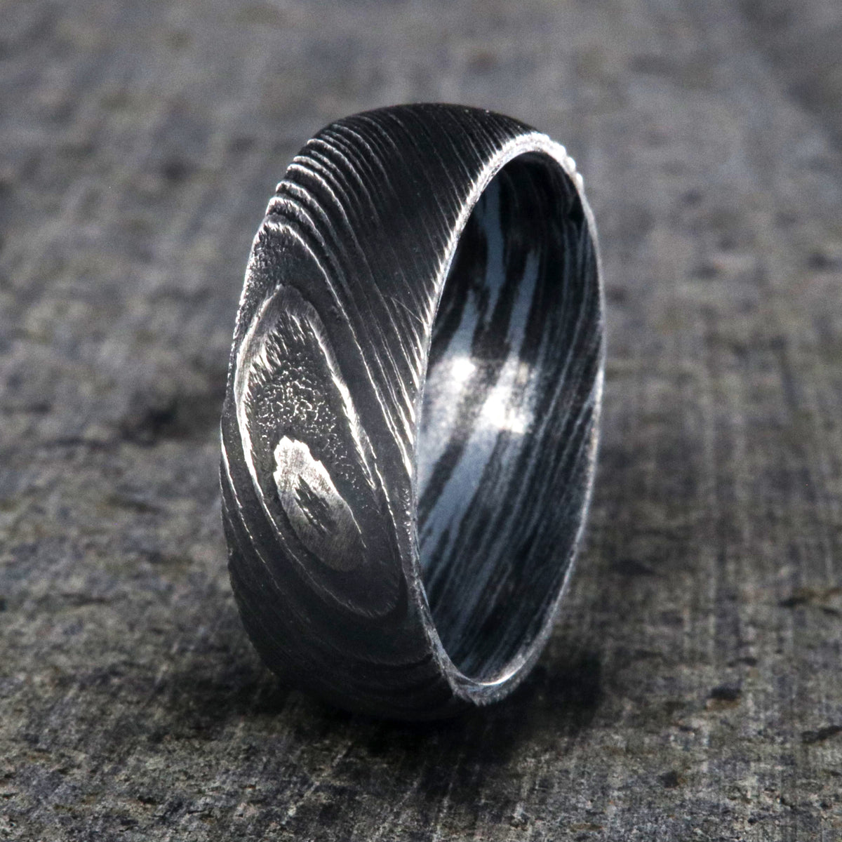 8mm wide Damascus steel wedding ring for men with a blue and black swirled cobaltium mokume sleeve