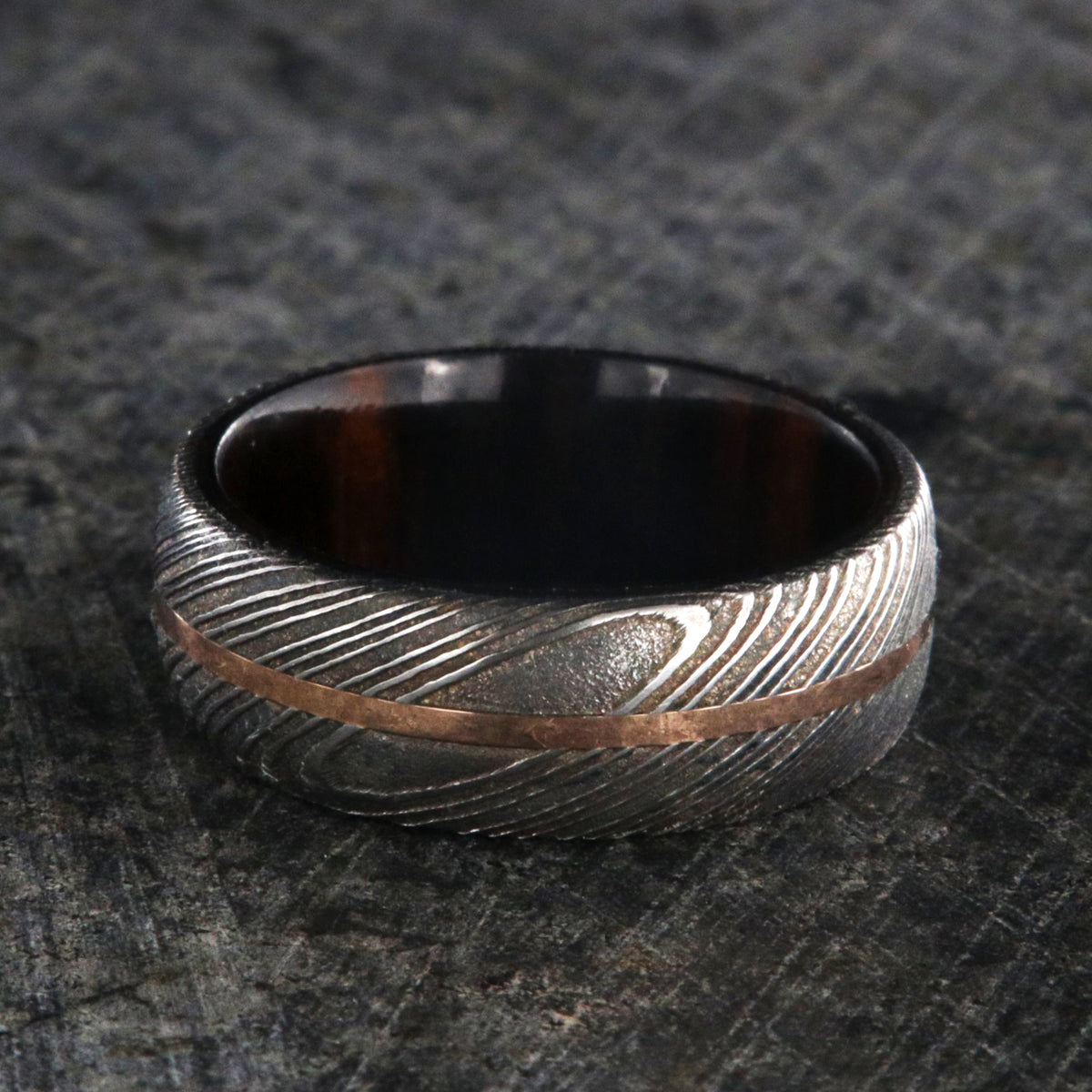 7mm wide men&#39;s Damascus steel wedding ring with a thin centered rose gold inlay and Arizona ironwood sleeve