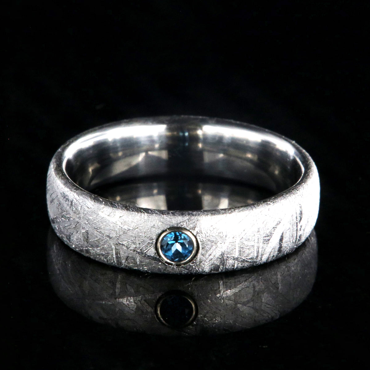 5mm wide women&#39;s meteorite ring with a blue topaz set in 14k gold bezel