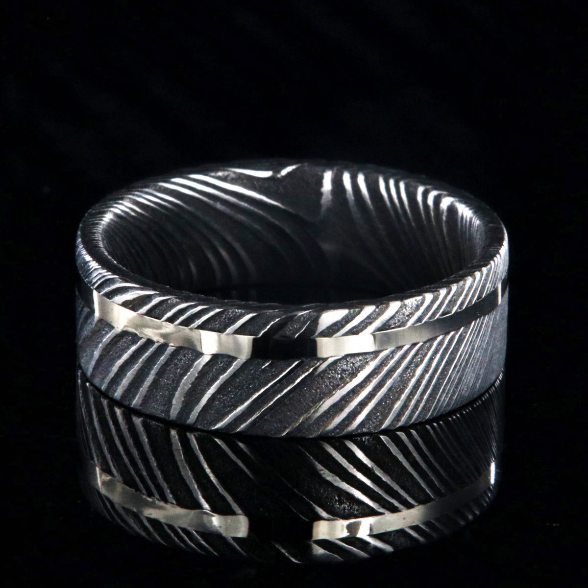 7mm wide black Damascus steel wedding ring with a white gold inlay