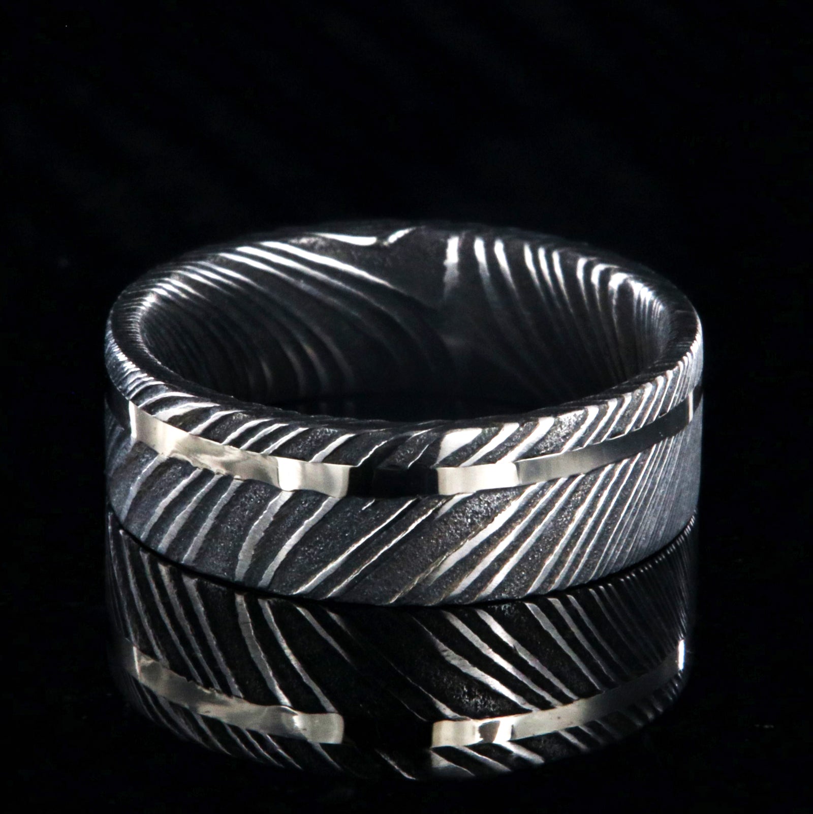 7mm wide black Damascus steel wedding ring with a white gold inlay