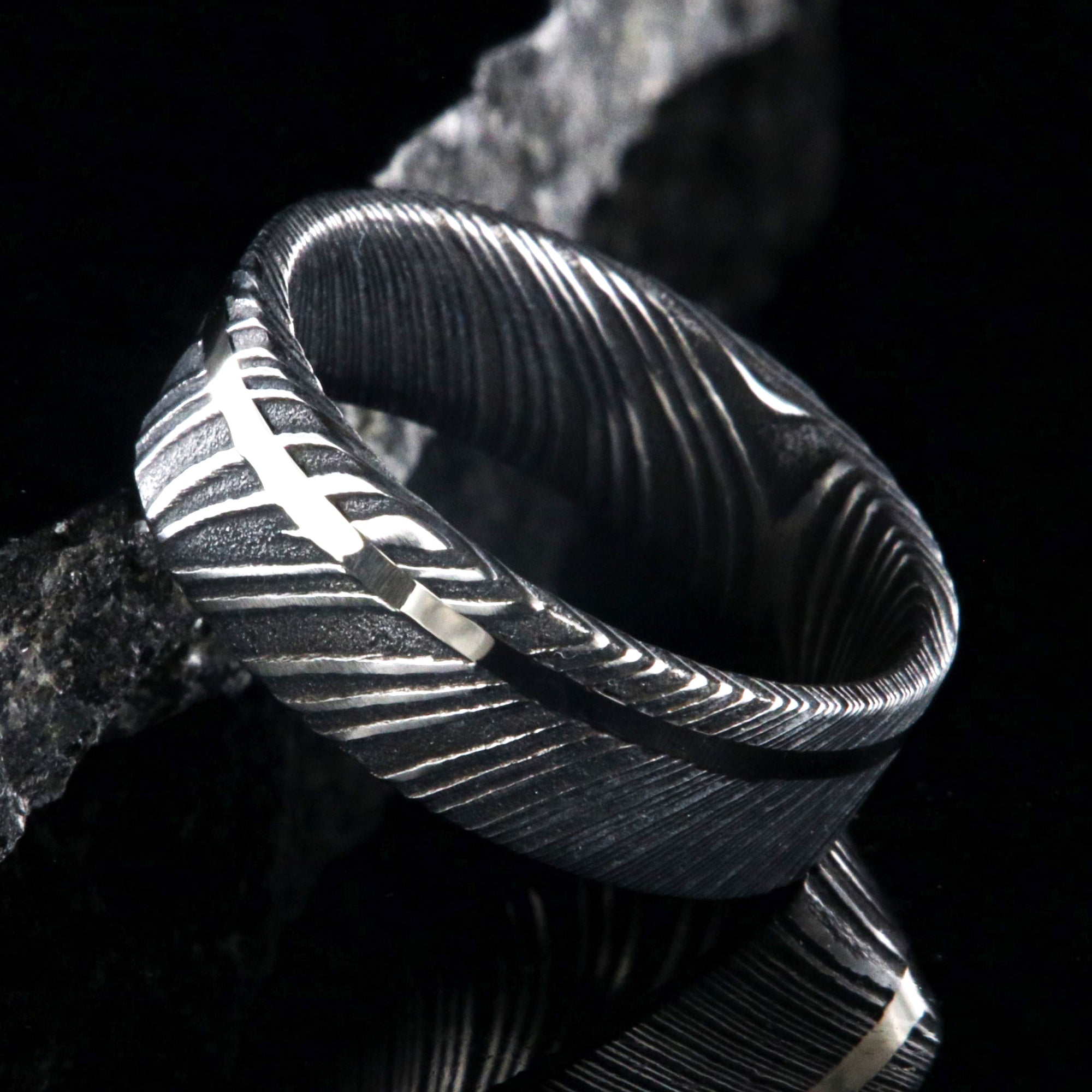 7mm wide black Damascus steel wedding ring with a white gold inlay