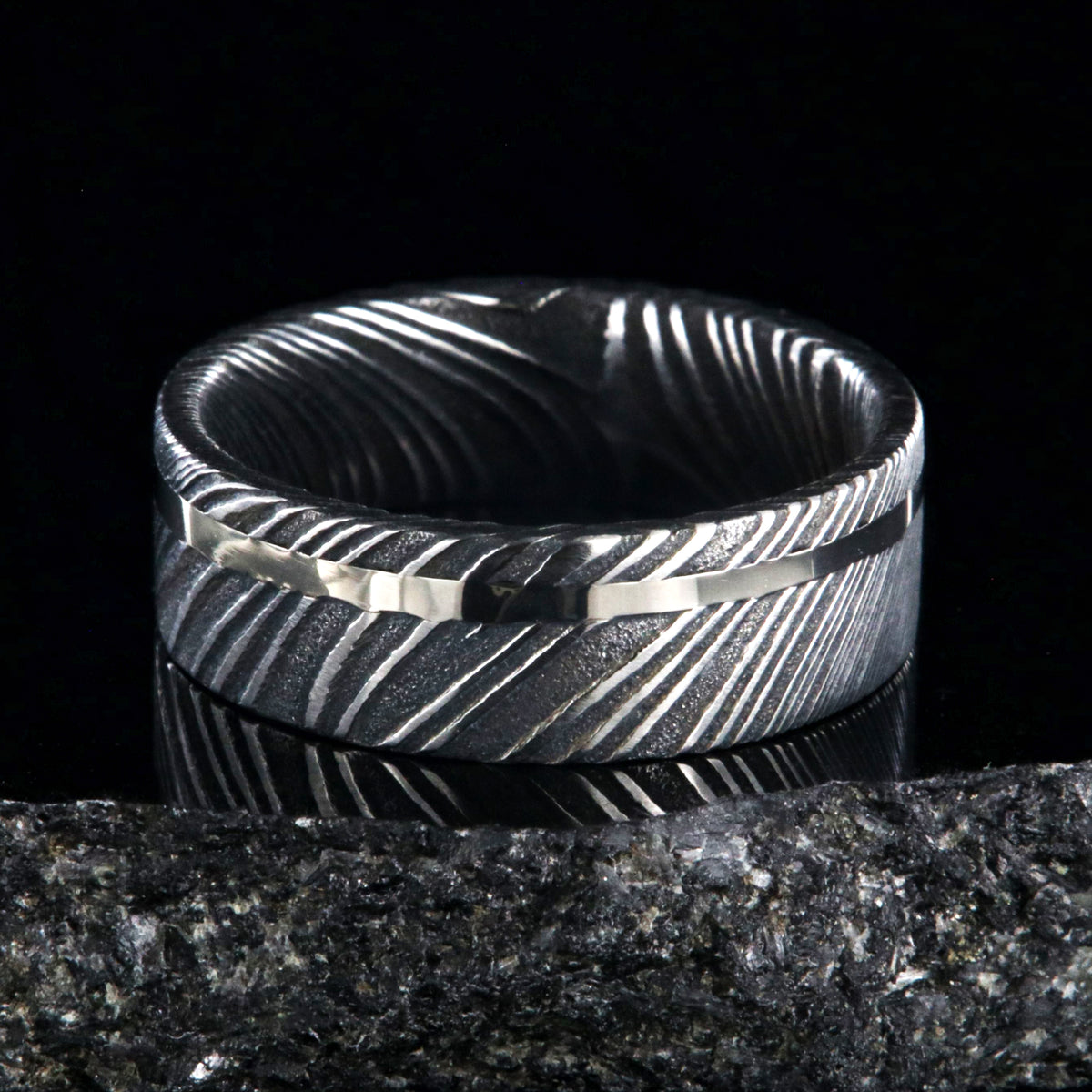 7mm wide black Damascus steel wedding ring with a white gold inlay