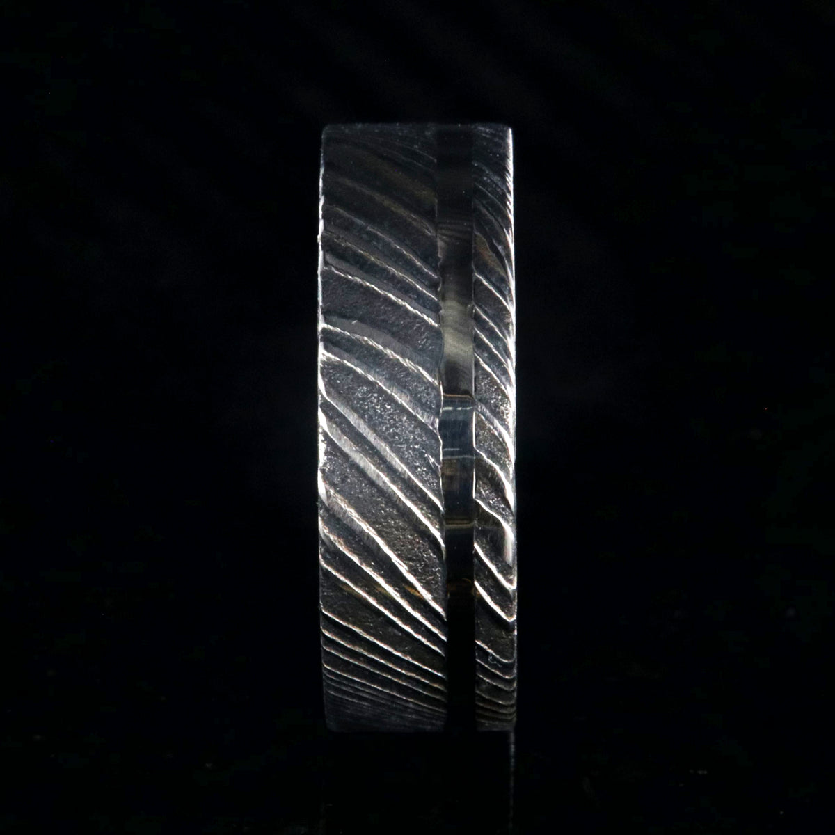 7mm wide black Damascus steel wedding ring with a white gold inlay