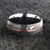 8mm wide black Damascus steel ring with two-tone pattern with a centered rose gold inlay and a big hammered finish