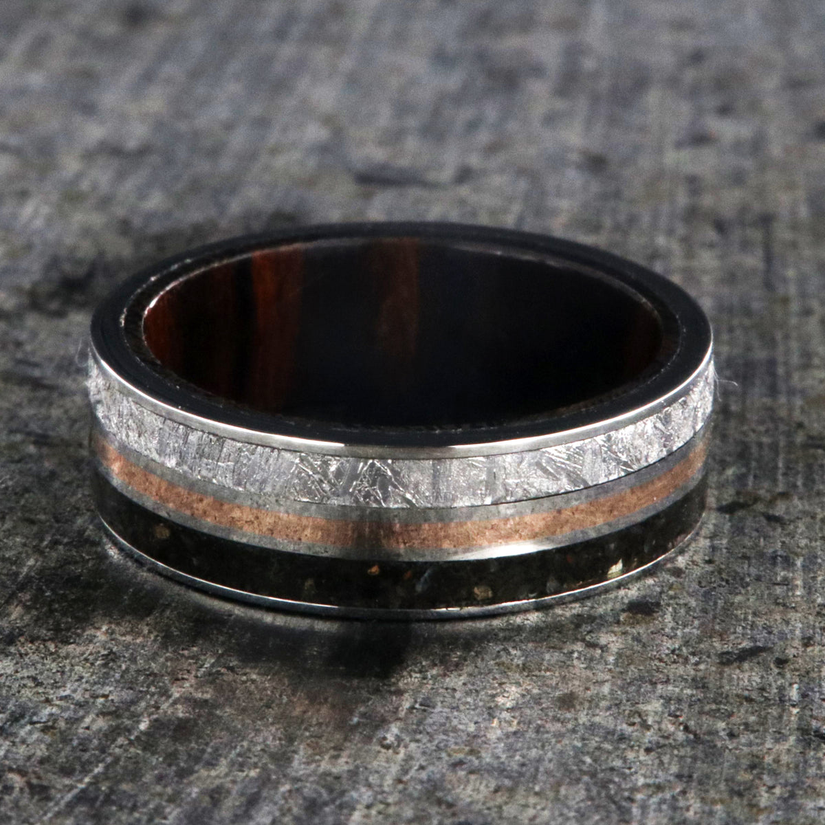 7mm wide wedding band with rose gold center inlay, Gibeon meteorite edge, dinosaur bone edge, and Arizona ironwood sleeve