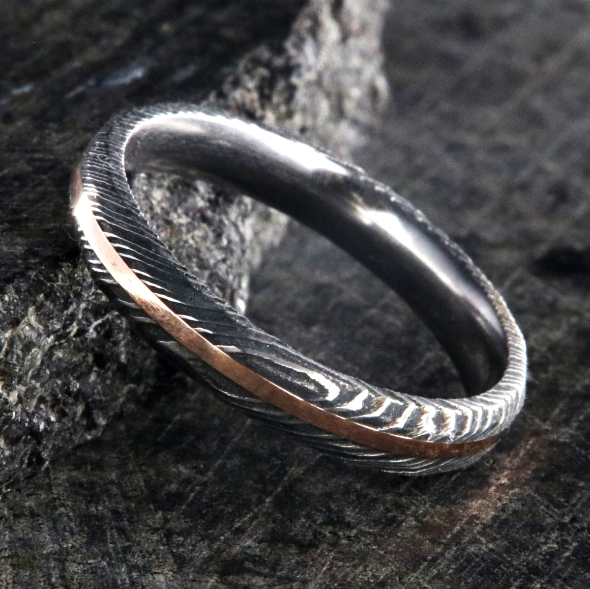 4mm wide Damascus steel wedding band with a rose gold inlay and hammered finish