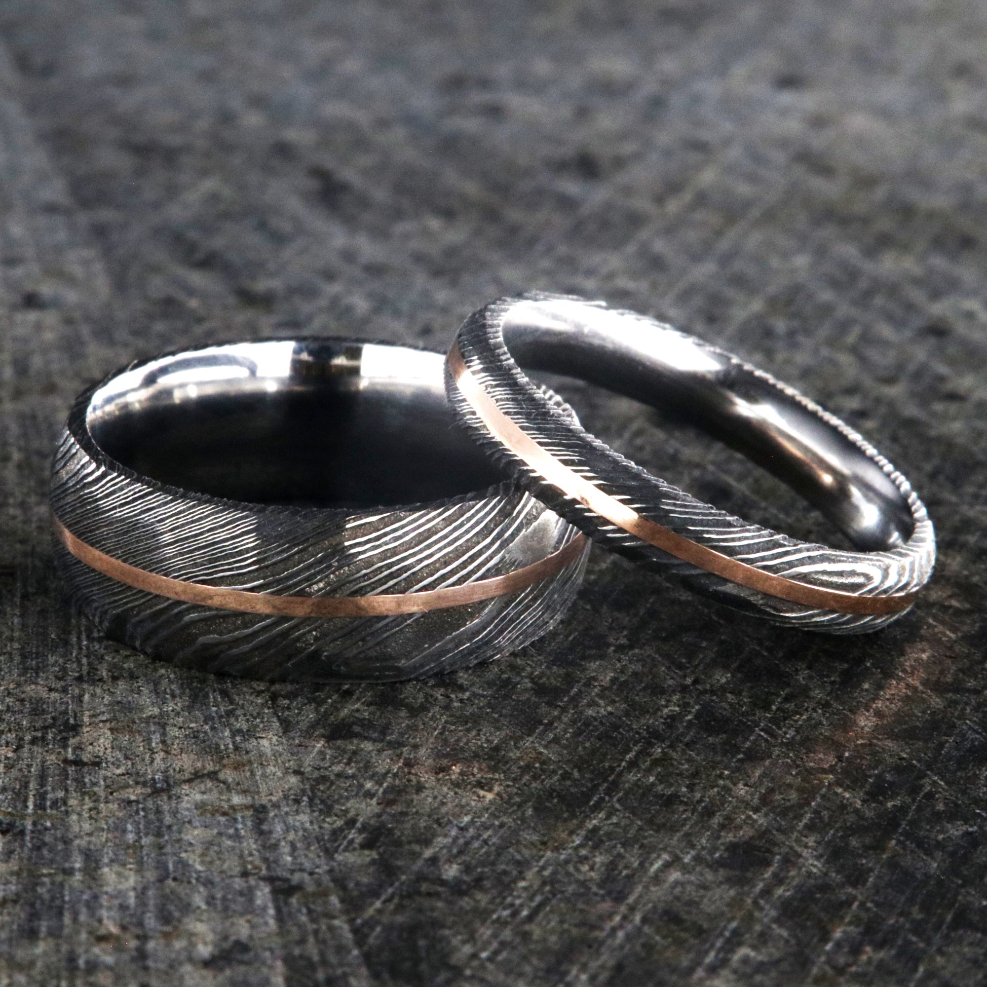 8mm and 4mm wide Damascus steel wedding ring set with a hammered finish and centered rose gold inlay