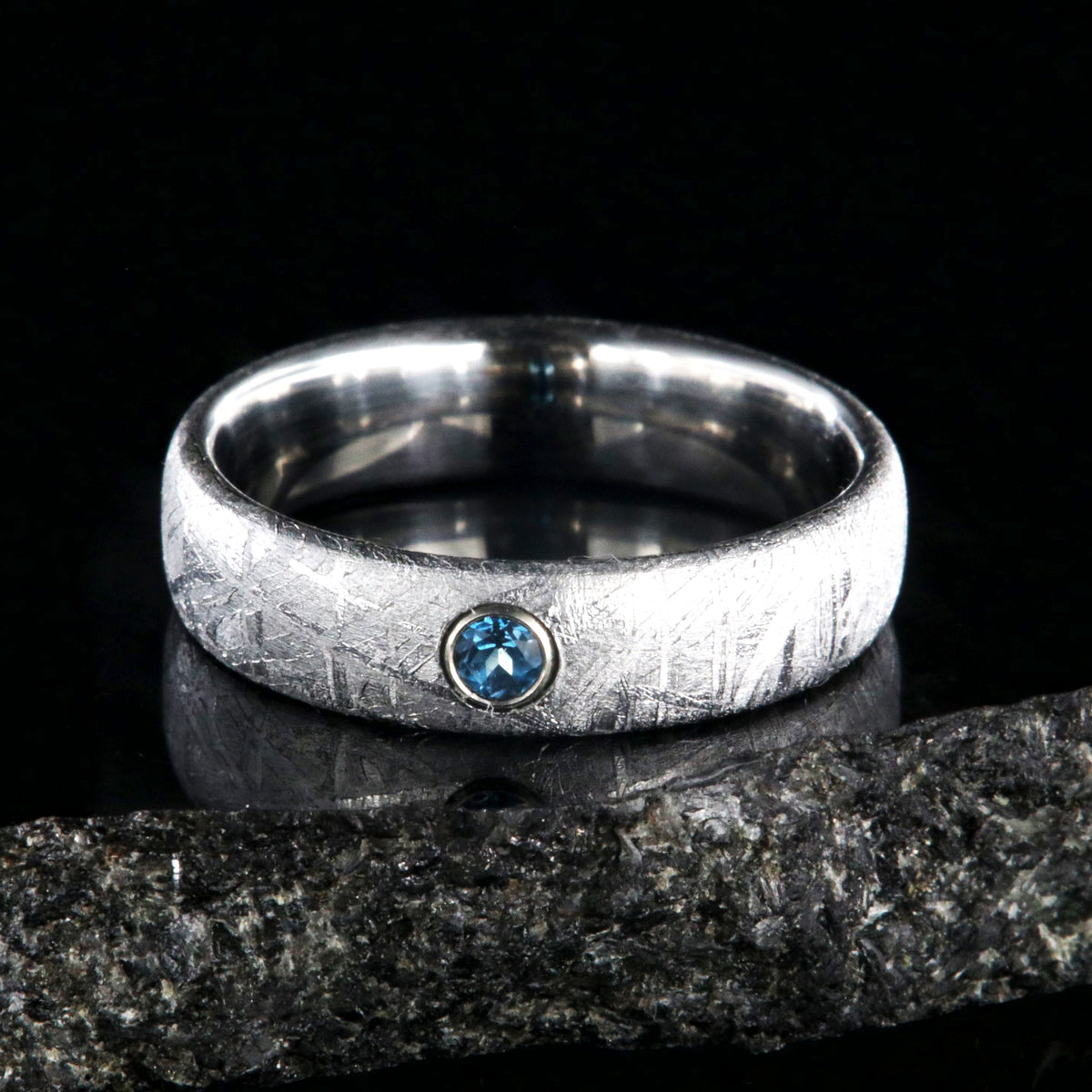 5mm wide women&#39;s meteorite ring with a blue topaz set in 14k gold bezel