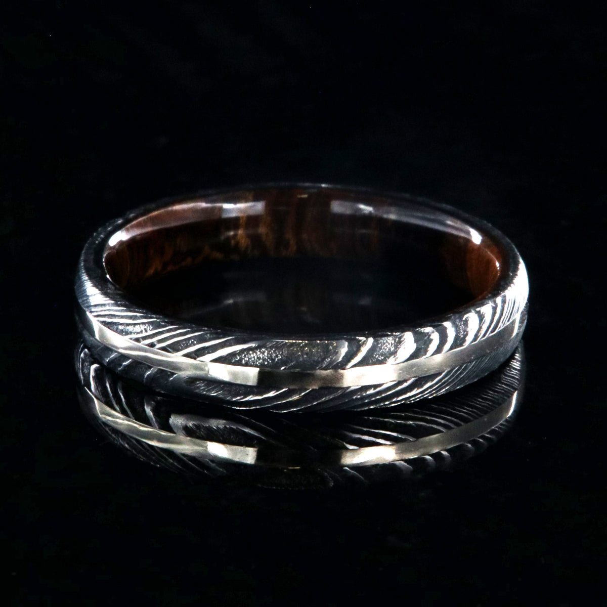 4mm wide black Damascus steel wedding band with a white gold inlay, Arizona ironwood sleeve, and a rounded profile