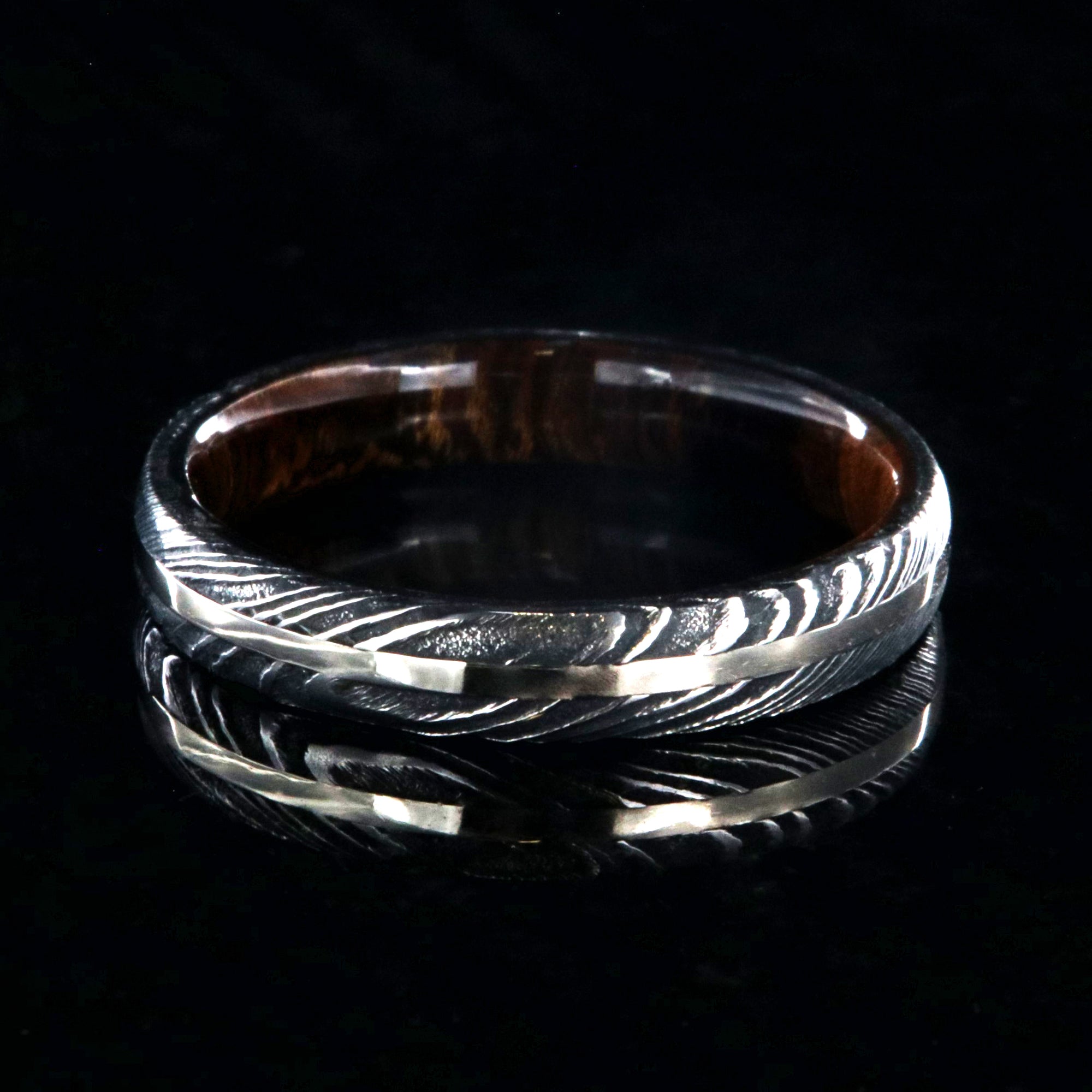 4mm wide black Damascus steel wedding band with a white gold inlay, Arizona ironwood sleeve, and a rounded profile