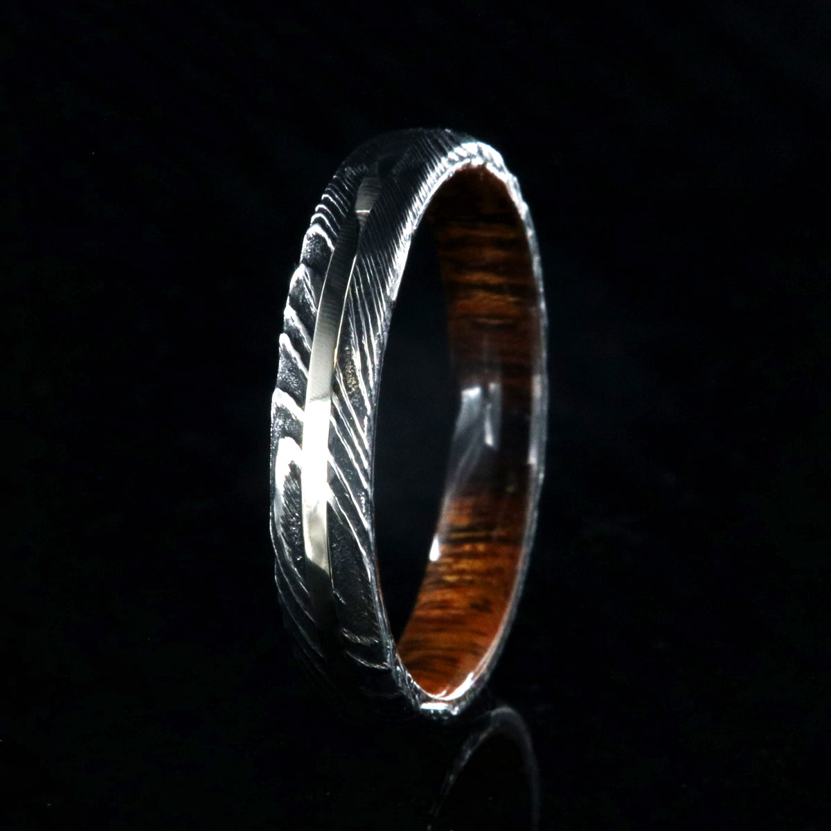 4mm wide black Damascus steel wedding band with a white gold inlay, Arizona ironwood sleeve, and a rounded profile