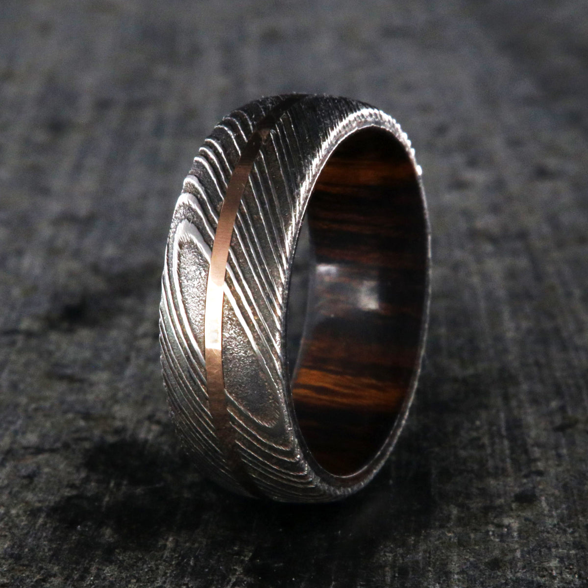 7mm wide men&#39;s Damascus steel wedding ring with a thin centered rose gold inlay and Arizona ironwood sleeve